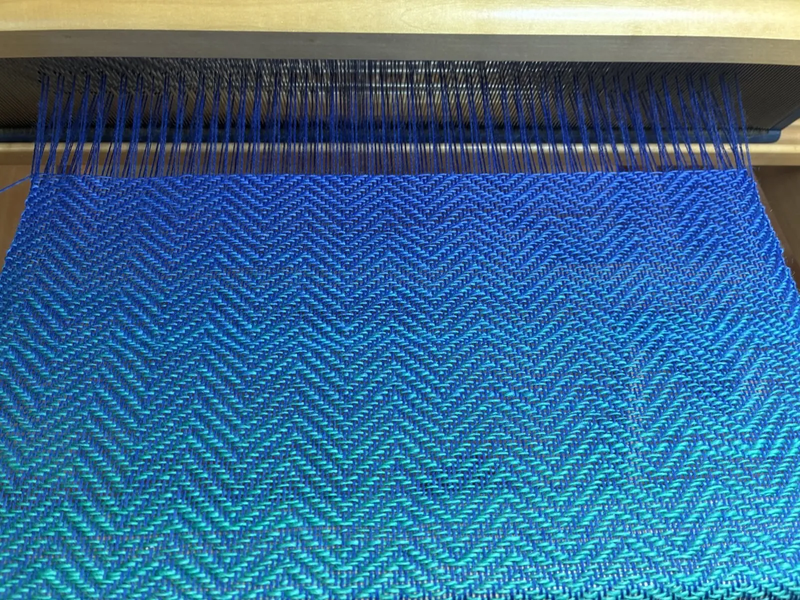 Gewebe in Blau- und Grüntönen auf dem Webstuhl